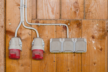 AC electrical power sockets including industrial high voltage sockets on a wooden wall