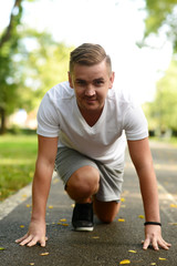 Blond man getting ready to run on a running track