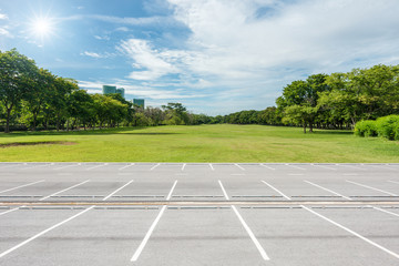 Empty parking lot against green lawn in city park