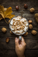 Hand holding a cup of cocoa with marshmallows. Autumn Still Life