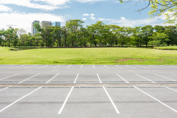 Obraz premium Empty parking lot against green lawn in city park