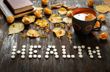 Concept of cold autumn - pills, leaves on dark wood