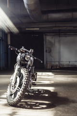 Naklejka premium motorcycle standing in dark building in rays of sunlight