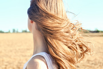 Girl stands outdoors, wind flutters her long hair
