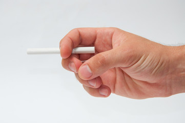 Men's hand holds a cigarette on gradient gray background