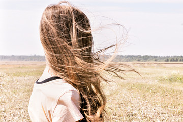 Girl stands outdoors, wind flutters her long hair