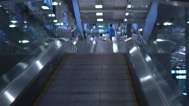 People moving on flat escalators in a airport terminal or train station. Slow motion