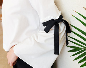 long white sleeve with black string bow tie style details. Close up trendy fashion.