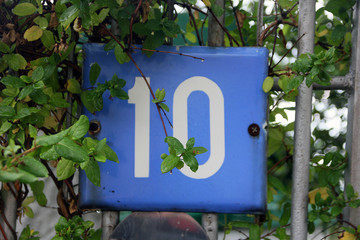 blue square metal number plate with the number ten among the gre