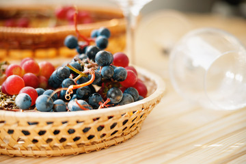 Fresh grape in the wicker basket and empty wine glasses 