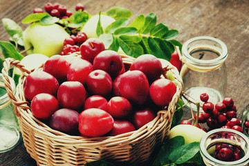 Plums in a basket, apples, rowanberry and glass jars 