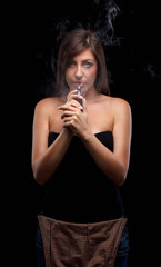 Young beautiful woman vaping e - cigarette. Black background.