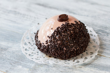 Half sphere dessert with glaze. Small cake on gray background. Sweet dish with cream filling. Smooth sugar glaze.