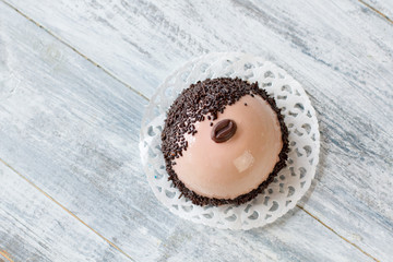 Top view of decorated dessert. Glaze of beige color. Coffee mousse cake in restaurant. Sugar icing and cream filling.