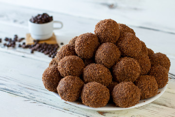 Brown candies on white plate. Pile of dark sweets. Homemade chocolate balls. Butter mixed with crumbled cookies.