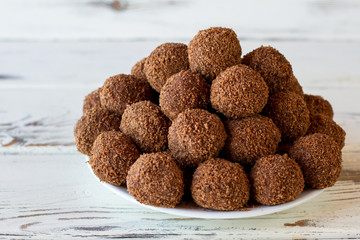Pile of candies on plate. Brown sweets with crumbs. Simple recipe of chocolate balls. Cocoa and crumbled cookies.