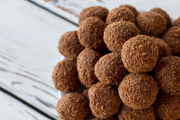 Brown colored sweets. Ball shaped candies with crumbs. Dessert with cocoa powder. Sweet dish high in calories.