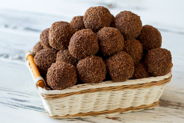 Brown sweets in a basket. Small desserts with crumbs. Chocolate balls cooked at home. Butter and cocoa powder.