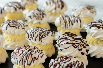 Desserts with meringue. Dark chocolate and yellow cream. Sweets in french cafe. Egg whites mixed with sugar.