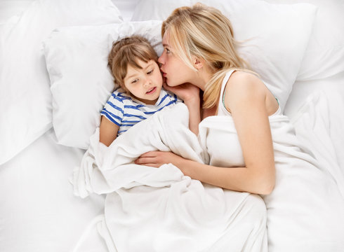 Mother and daughter whispering in bed