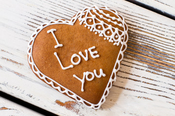 Cookie with inscription. Brown biscuit on wooden surface. Convey an important message. Dessert that tastes like love.