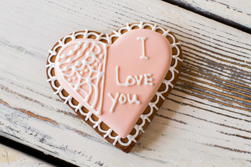 Heart shaped biscuit with inscription. Frosted cookie of pink color. Make a confession in love. Small present that brings joy.