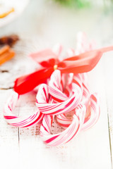 Candy canes and other Christmas decorations on white wooden rustic background, selective focus. Holiday concept, toned