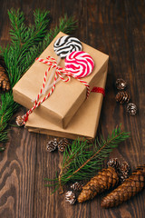 Hand crafted Christmas gifts on rustic wooden background with fir branches, cones and sweet candies. Vintage style. Holiday concept. Selective focus