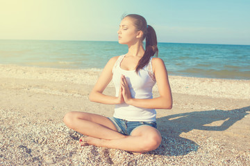 Fototapeta na wymiar young woman practicing yoga or fitness at seashore