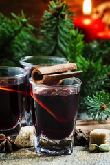 Mulled wine with orange and spices in small glasses on the backg