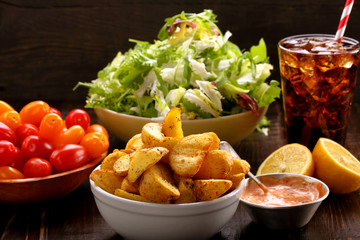 Roasted potatoes with dip and fresh salad on wooden table