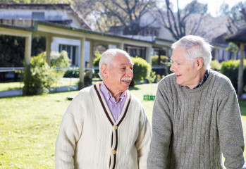 Happy retired men talking outdoor in a rehab facility garden