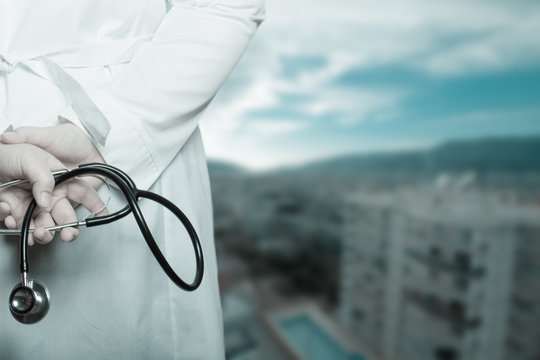 The doctor put his hands with stethoscope behind his back on a b
