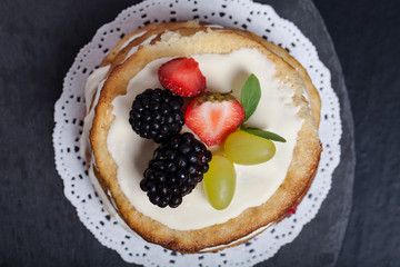 Biscuit homemade cake with cream and berries on black background