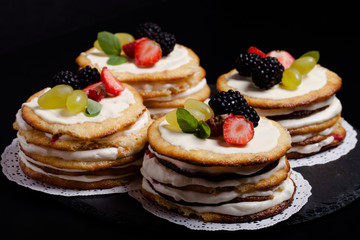Biscuit homemade cake with cream and berries on black background