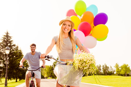 Portrait of beautiful woman with balloons and flowers riding bik