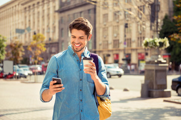 Happy guy having walk in the city and typing sms
