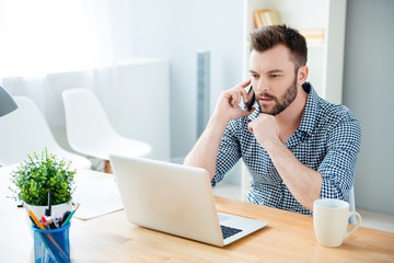 Concentrated handsome businessman talking on mobile phone in off