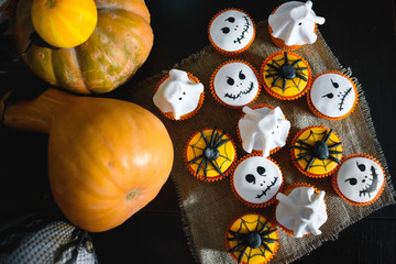 Group of halloween cupcakes made like monsters or ghosts for a delicious party with a fresh pumpkin...