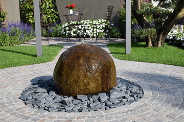 Kugel aus Naturstein als Brunnen im gestalteten Garten