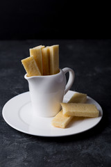 Stack of homemade english shortbread cookies in a milk jug on a plate