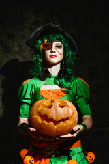 Halloween witch holds an orange pumpkin