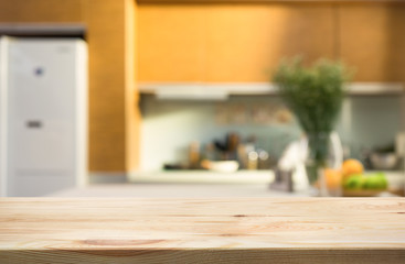 Wood table top island with blur kitchen room interior in morning