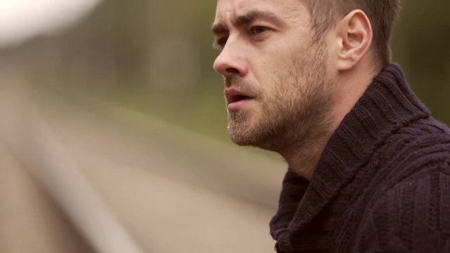 Man smokes on the rails. / Sad man sitting on the rails and smoke. close up.