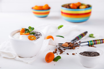 Yogurt with kumquats ,Chia seeds,and granola on a white background.Healthy food or diet concept.selective focus.