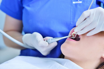 A pretty young woman with a bright, white smile lying in the dentist's chair having a checkup