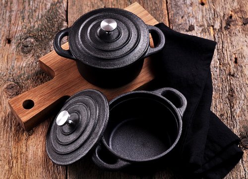 The small cast iron pan and cutting board on wooden background
