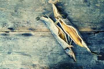 Two salty fishes of a pike on an old wooden surface of a table. Dry salted river fish