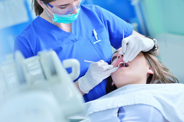 A pretty young woman with a bright, white smile lying in the dentist's chair having a checkup