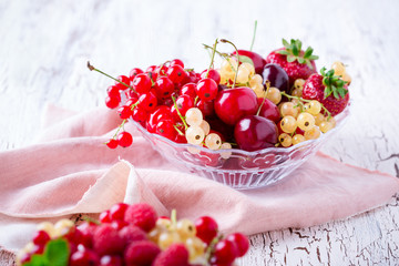 Fresh summer berries and fruits in glass bowl